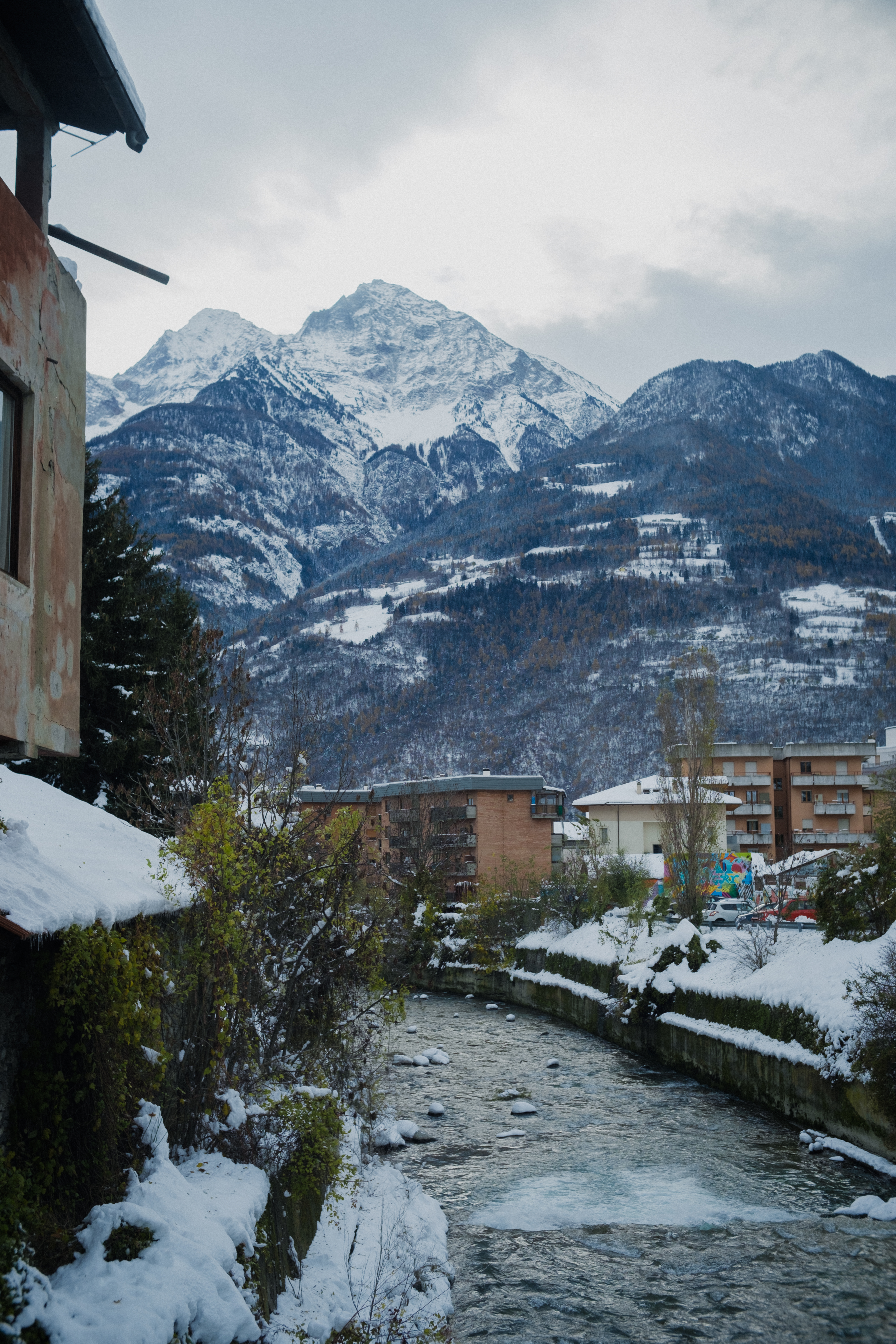Snow-covered alpine village with a stream running through